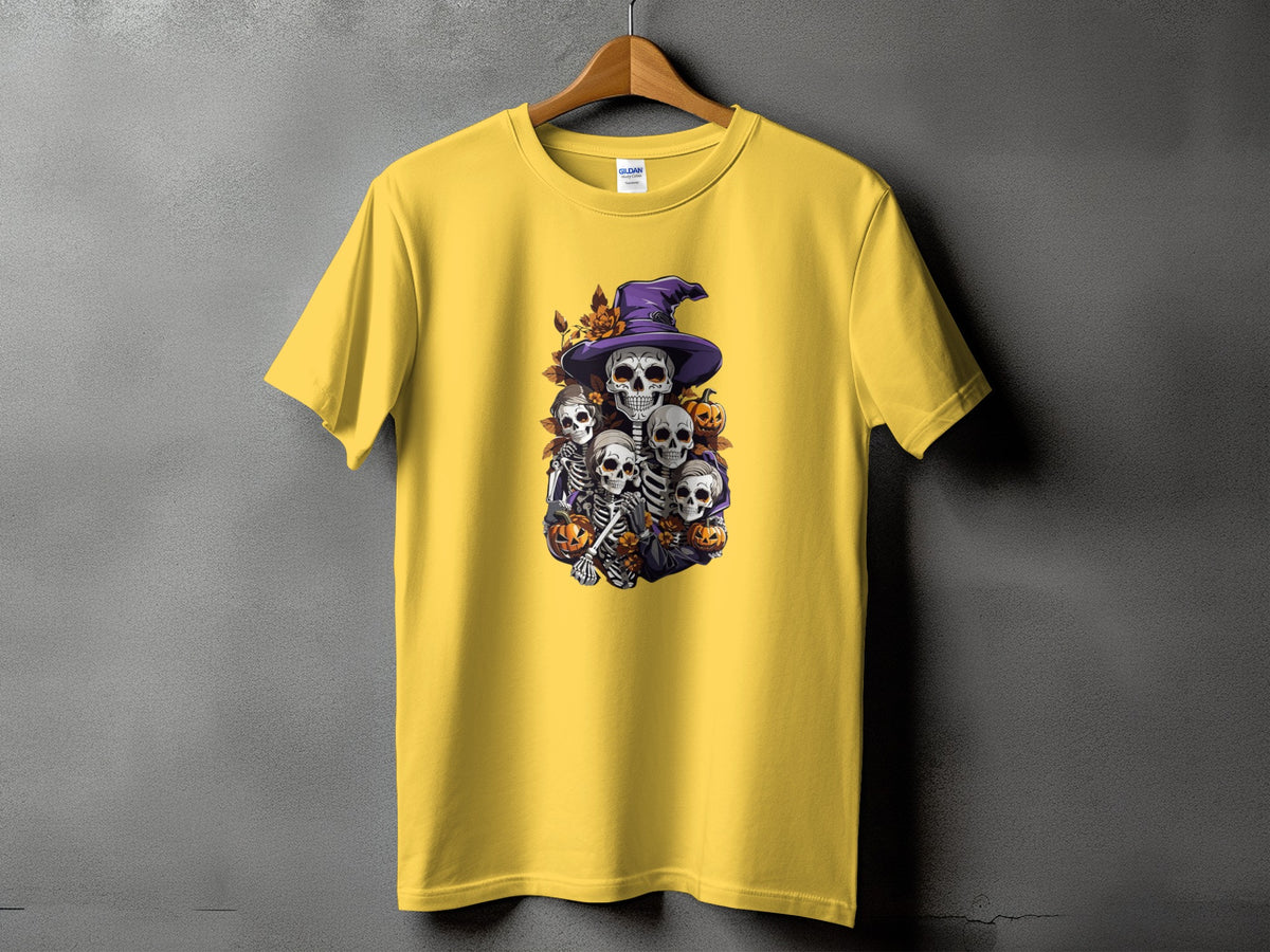 Yellow t-shirt with Halloween-themed graphic of skeletons and pumpkins under a witch's hat.