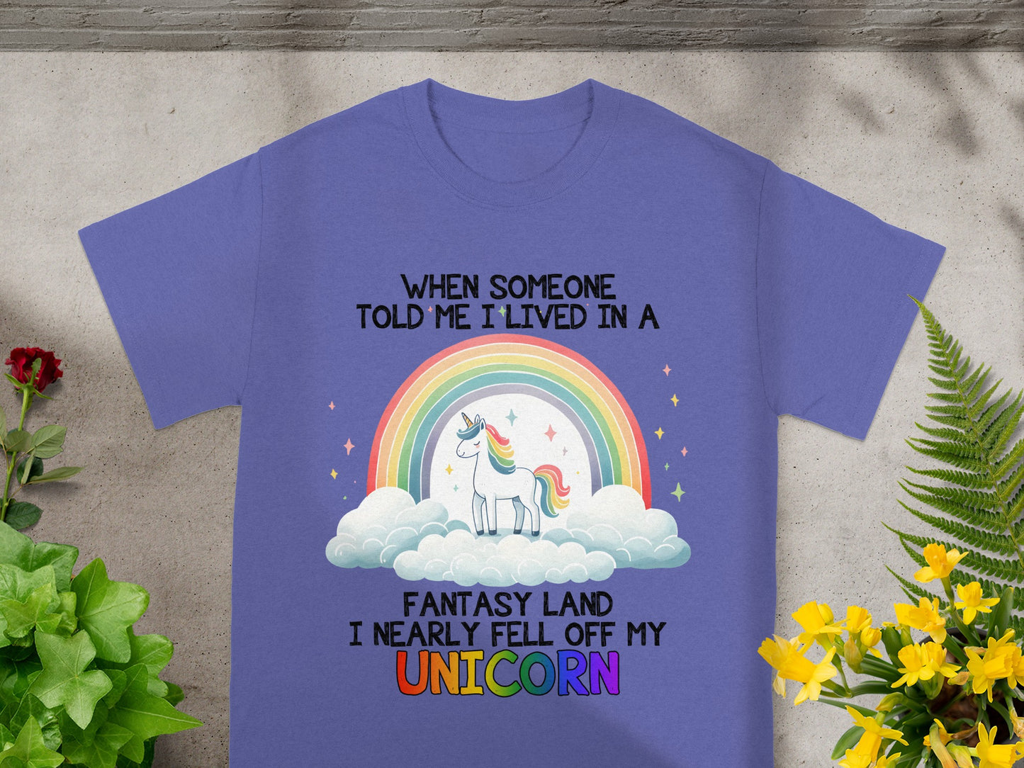 Purple t-shirt with a unicorn, rainbow, clouds, and the text "When someone told me I lived in a fantasy land I nearly fell off my unicorn."