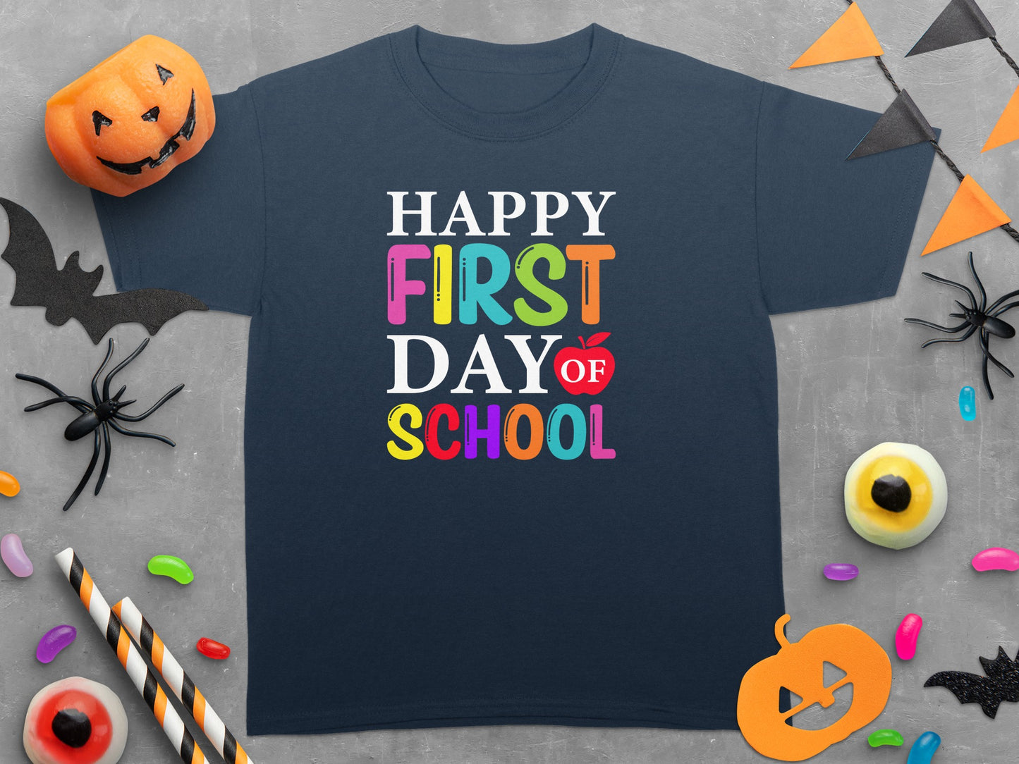 Happy First Day of School text with colorful letters and an apple accent on a dark shirt.