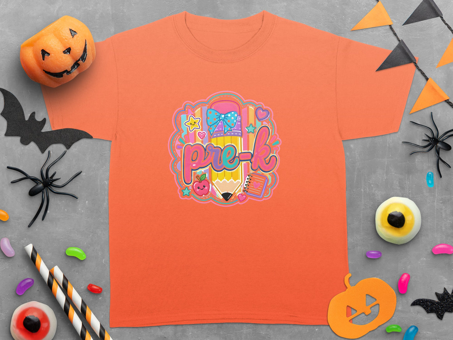 Orange t-shirt with "pre-k" text, a pencil, apple, bow, and notebook graphic.