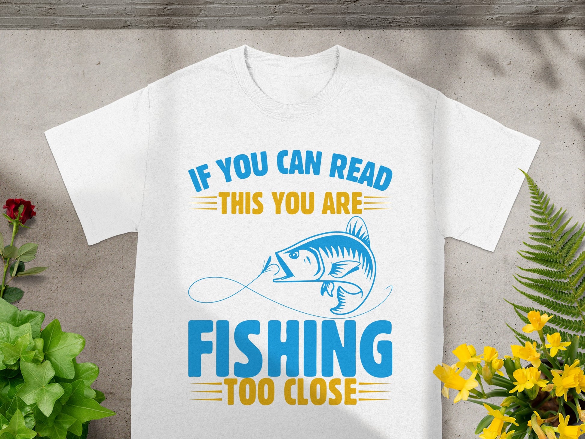 White t-shirt with blue text "IF YOU CAN READ THIS YOU ARE" and a fish graphic.