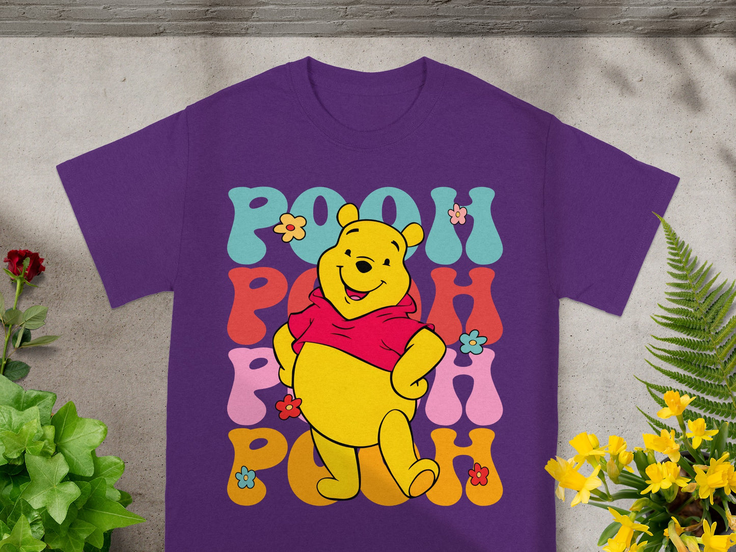 Winnie the Pooh graphic tee with "POOH" text in colorful floral font.