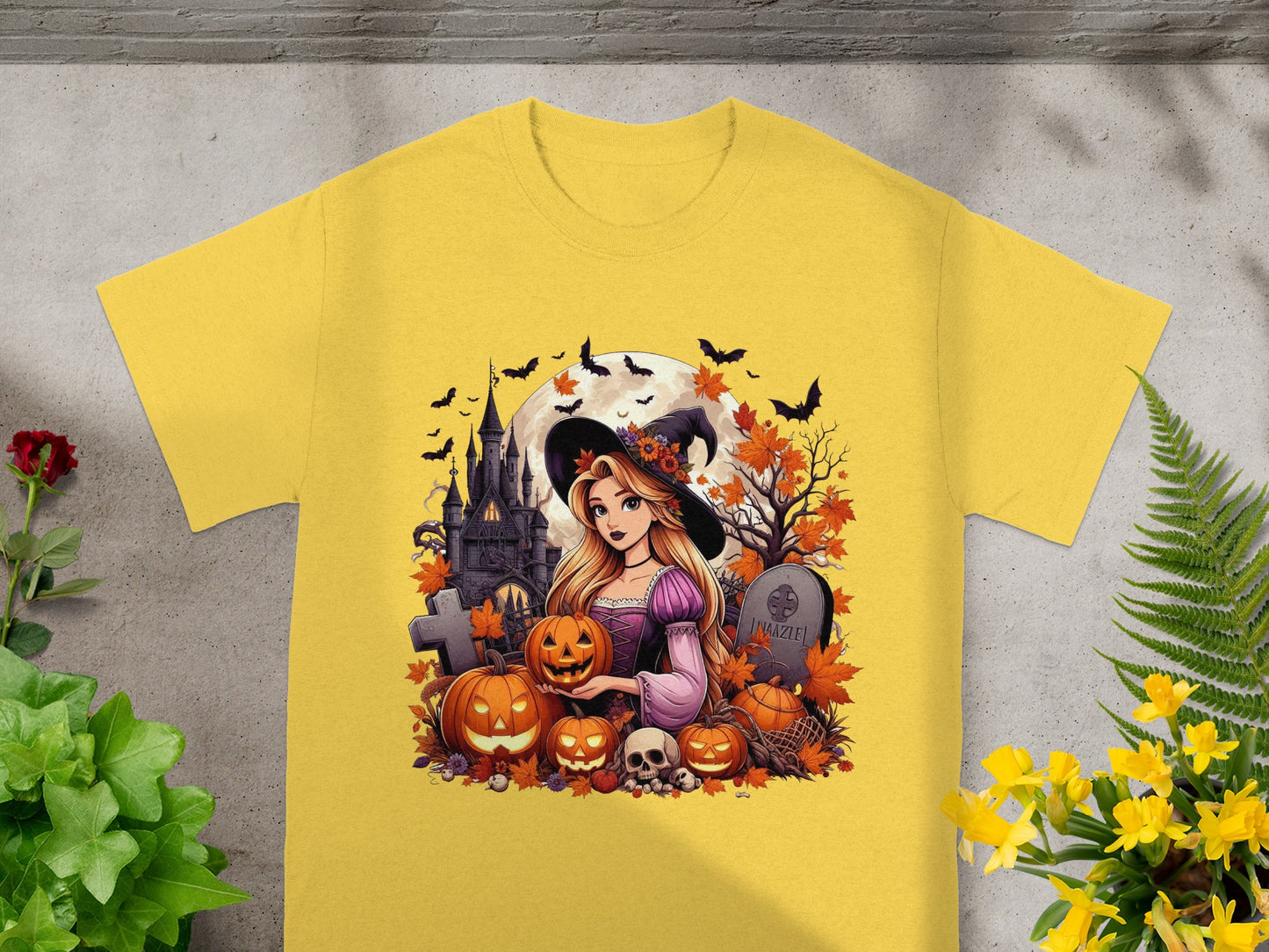 Girl in witch hat with pumpkins, castle, bats, and tombstone on yellow t-shirt.