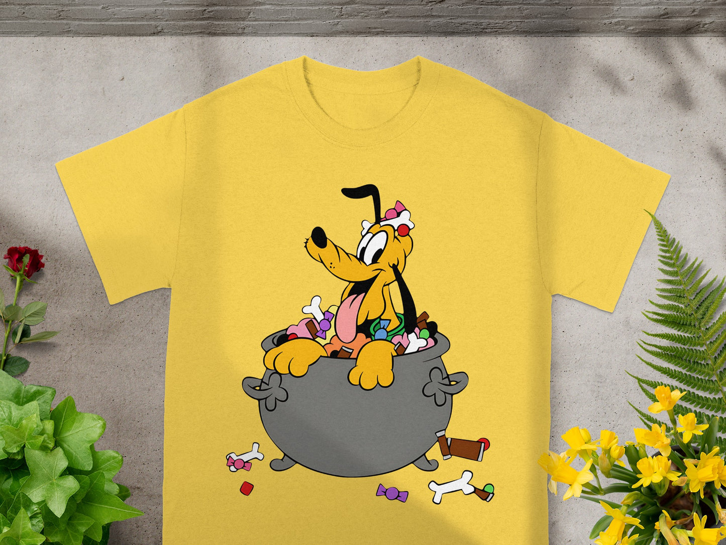 Yellow t-shirt with Pluto sitting in a cauldron full of candy and bones.