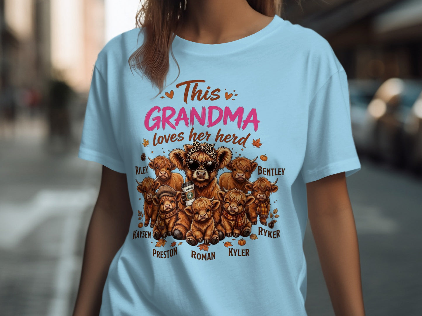 Light blue t-shirt with "This GRANDMA loves her herd" and highland cows.