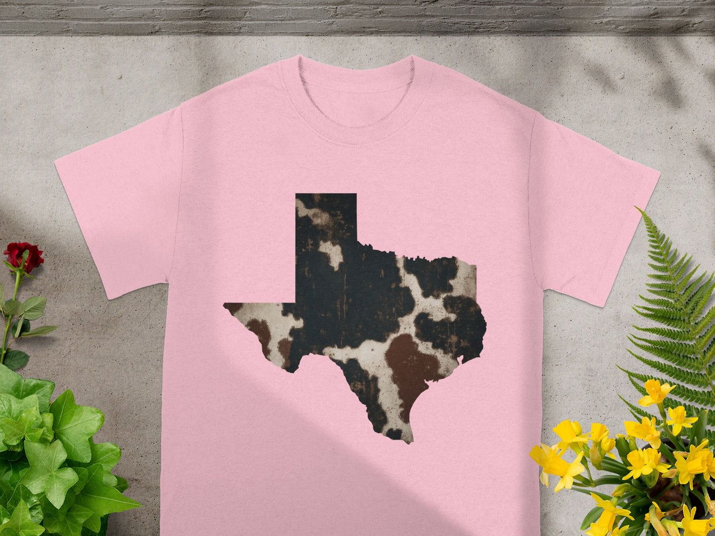 Pink t-shirt with cow print Texas outline graphic.
