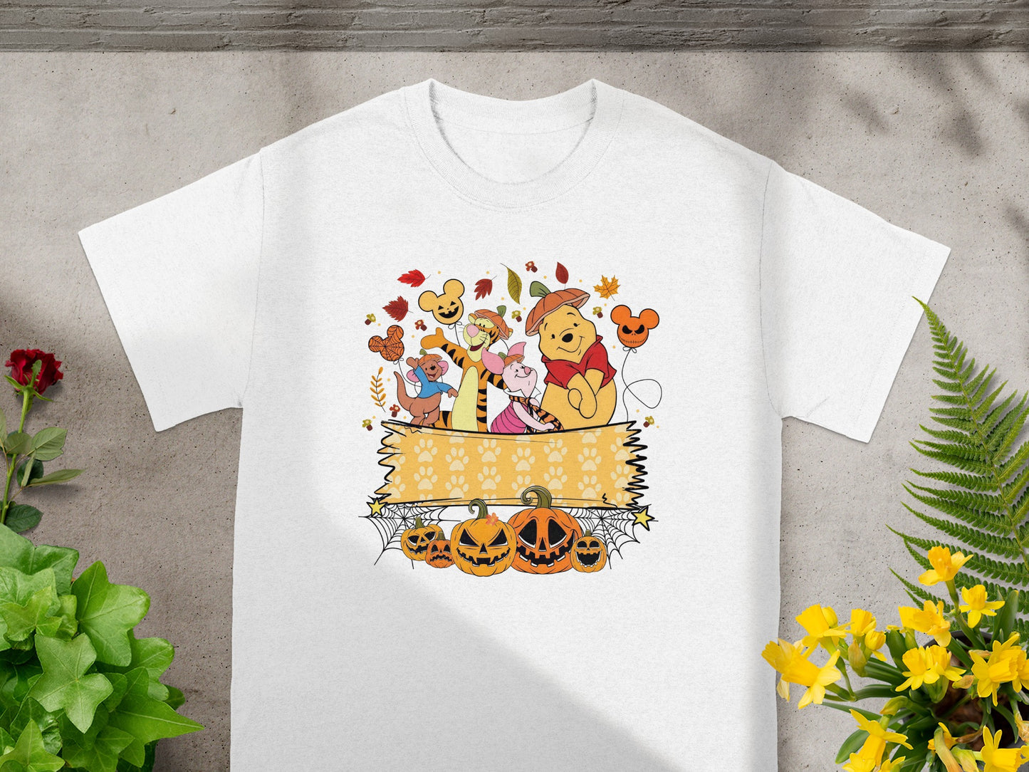 Winnie the Pooh characters with Halloween pumpkins and autumn leaves on a white t-shirt.