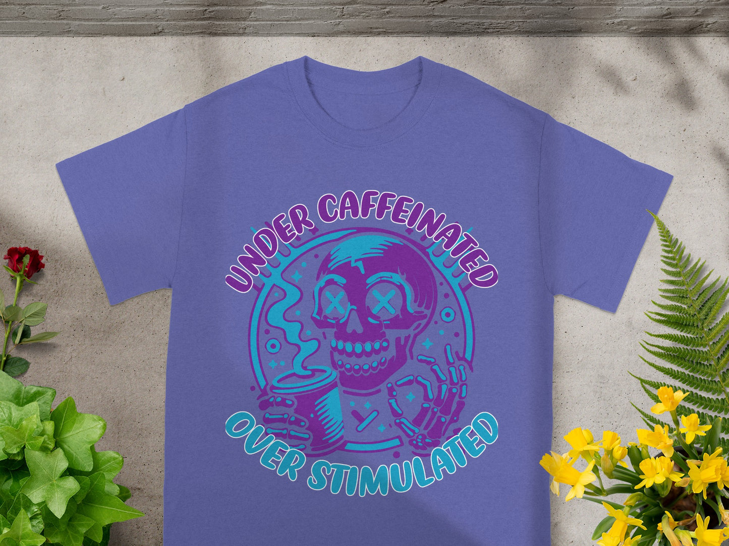 Purple t-shirt with a skull graphic and text "UNDER CAFFEINATED OVER STIMULATED".