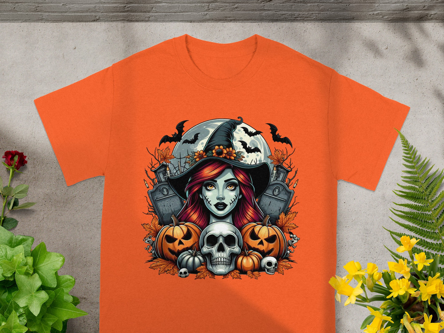 Orange t-shirt with a Halloween graphic of a witch, pumpkins, bats, and skulls.