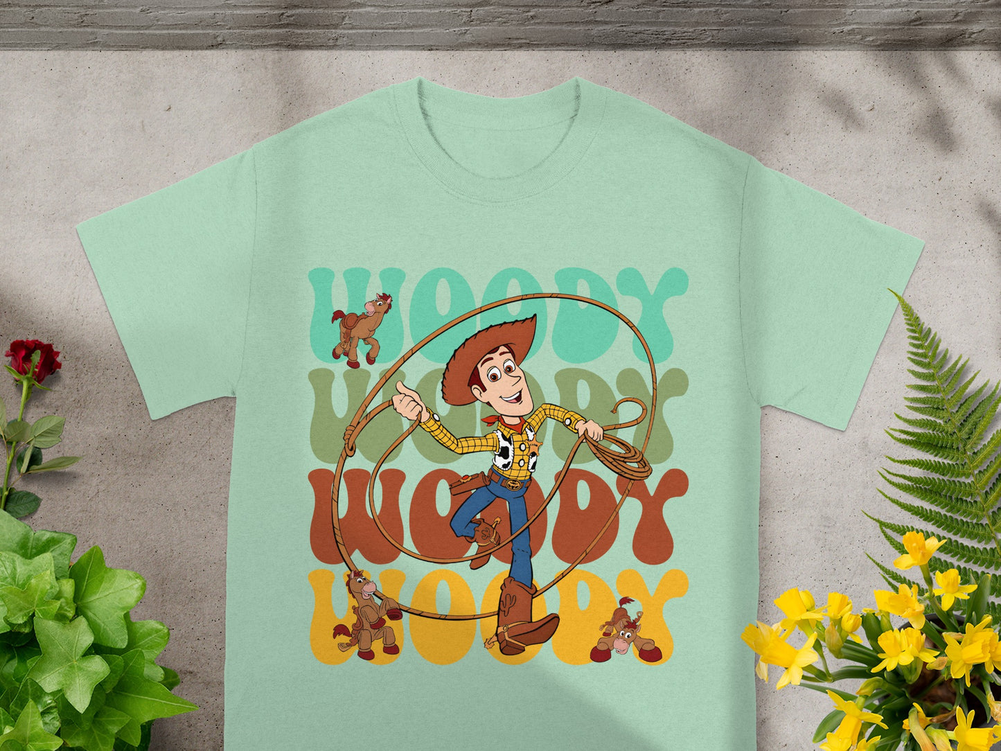 Woody from Toy Story with rope and toy horses on a light green t-shirt.