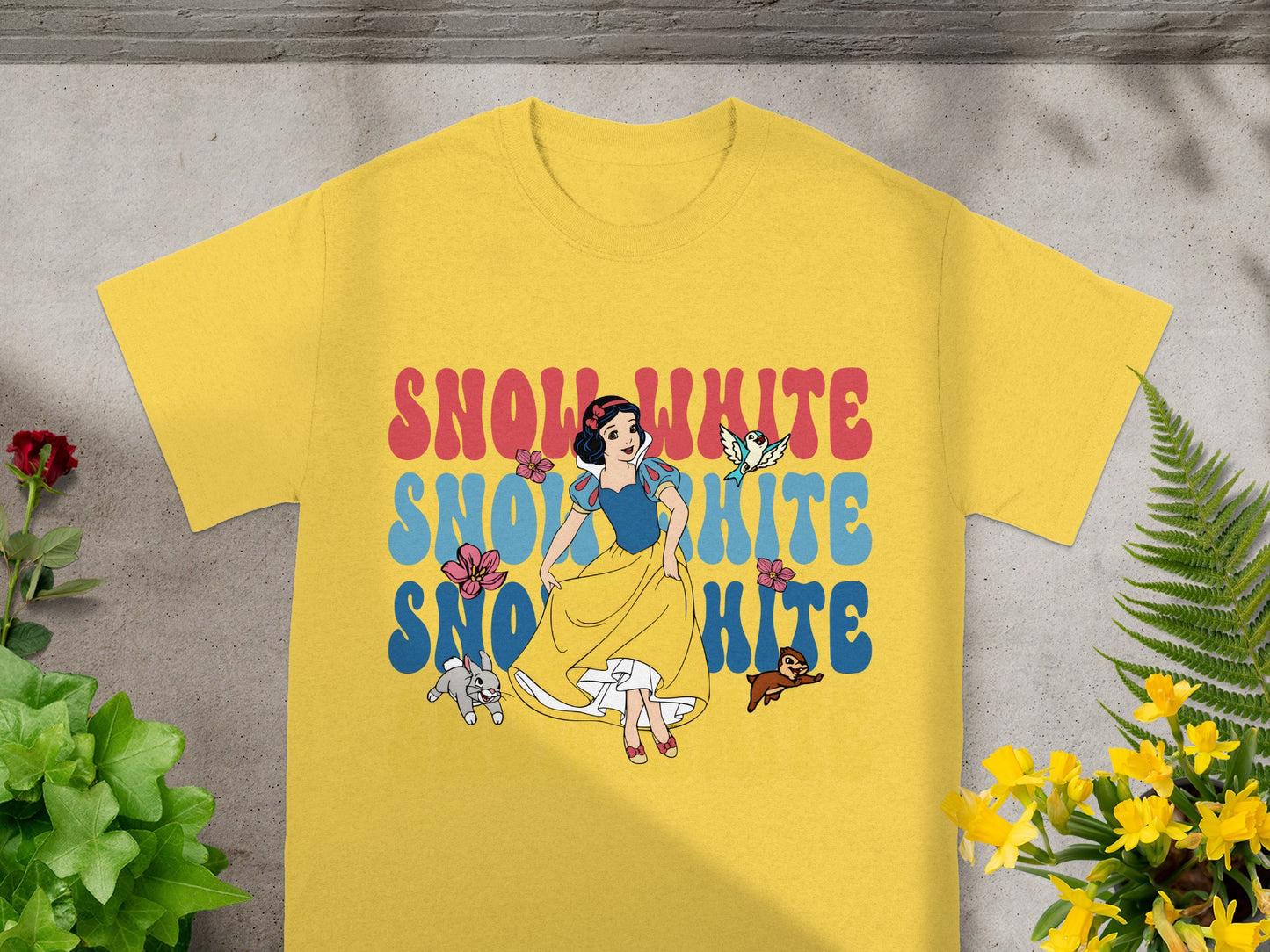 Snow White and bluebirds graphic on yellow t-shirt with floral accents.