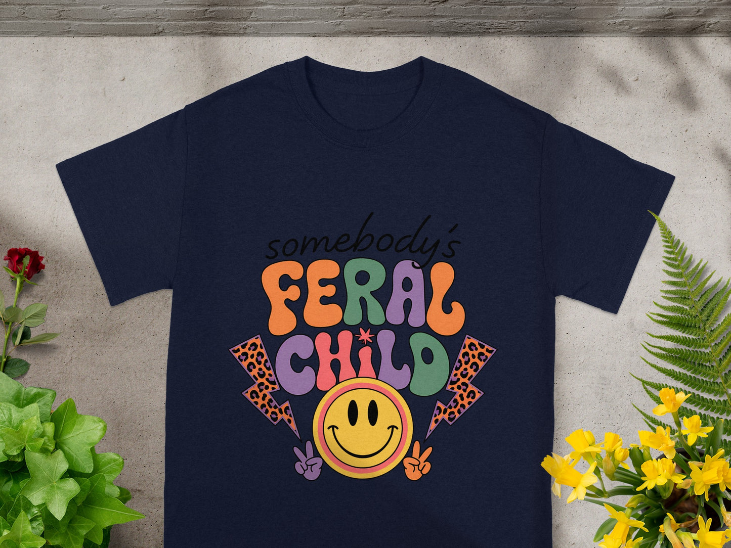 Navy t-shirt with "somebody's FERAL CHILD" text, smiley face, and lightning bolts.