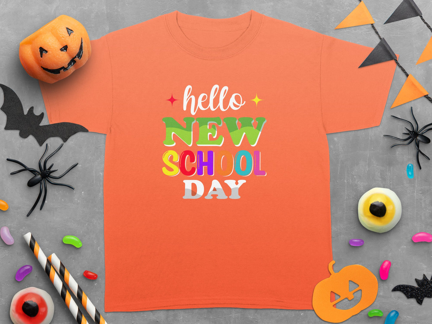 Orange t-shirt with "hello NEW SCHOOL DAY" in colorful text, surrounded by Halloween decor.