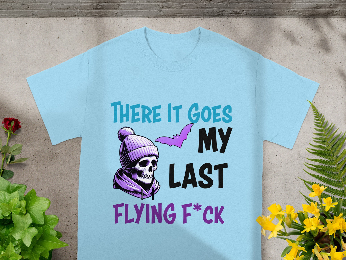 Light blue t-shirt with skull wearing purple beanie and text "There it goes my last flying f*ck".