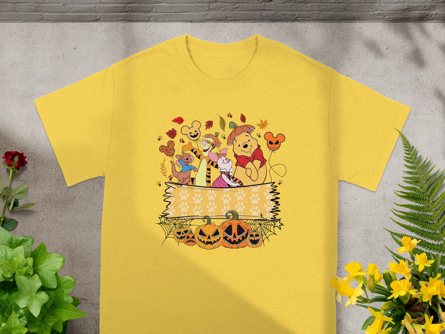 Winnie the Pooh characters with pumpkins and autumn leaves on a yellow t-shirt.