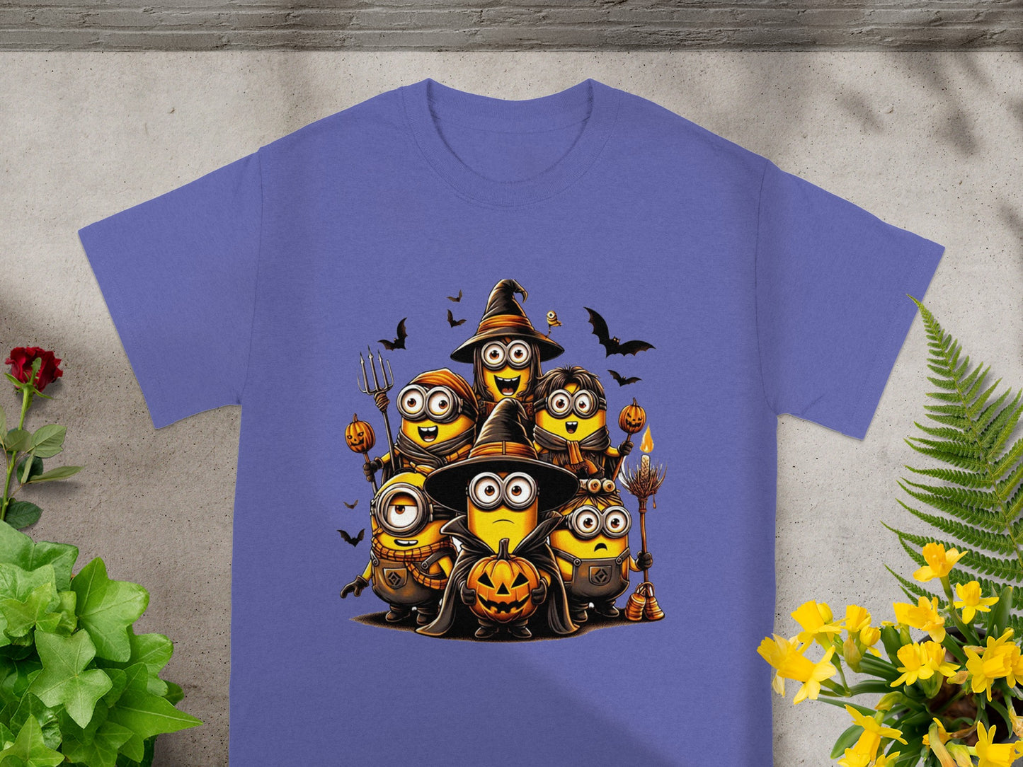 Minions in Halloween costumes with pumpkins and bats printed on a purple t-shirt.