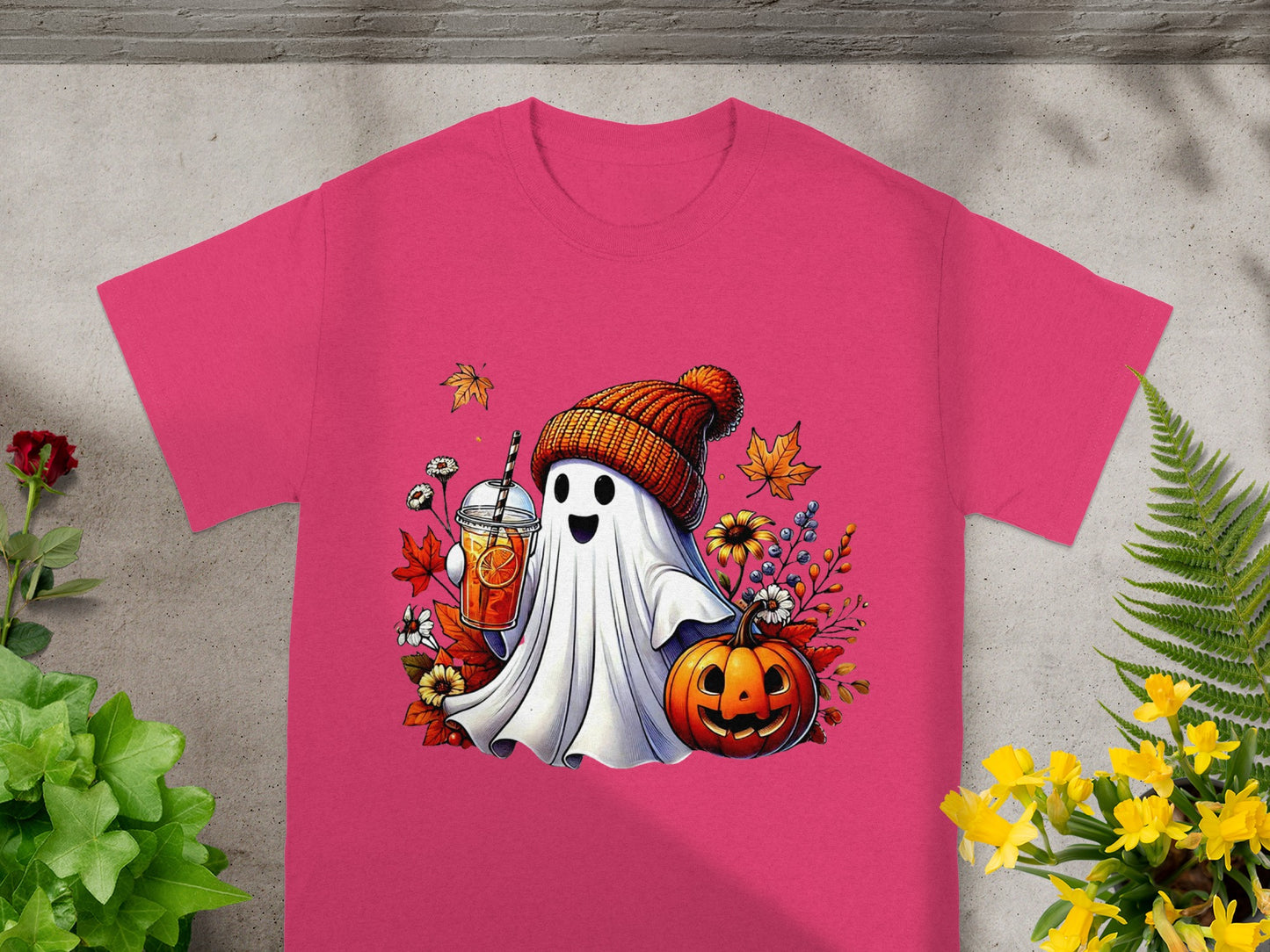 Ghost holding a drink with pumpkin and autumn leaves graphic on pink t-shirt.