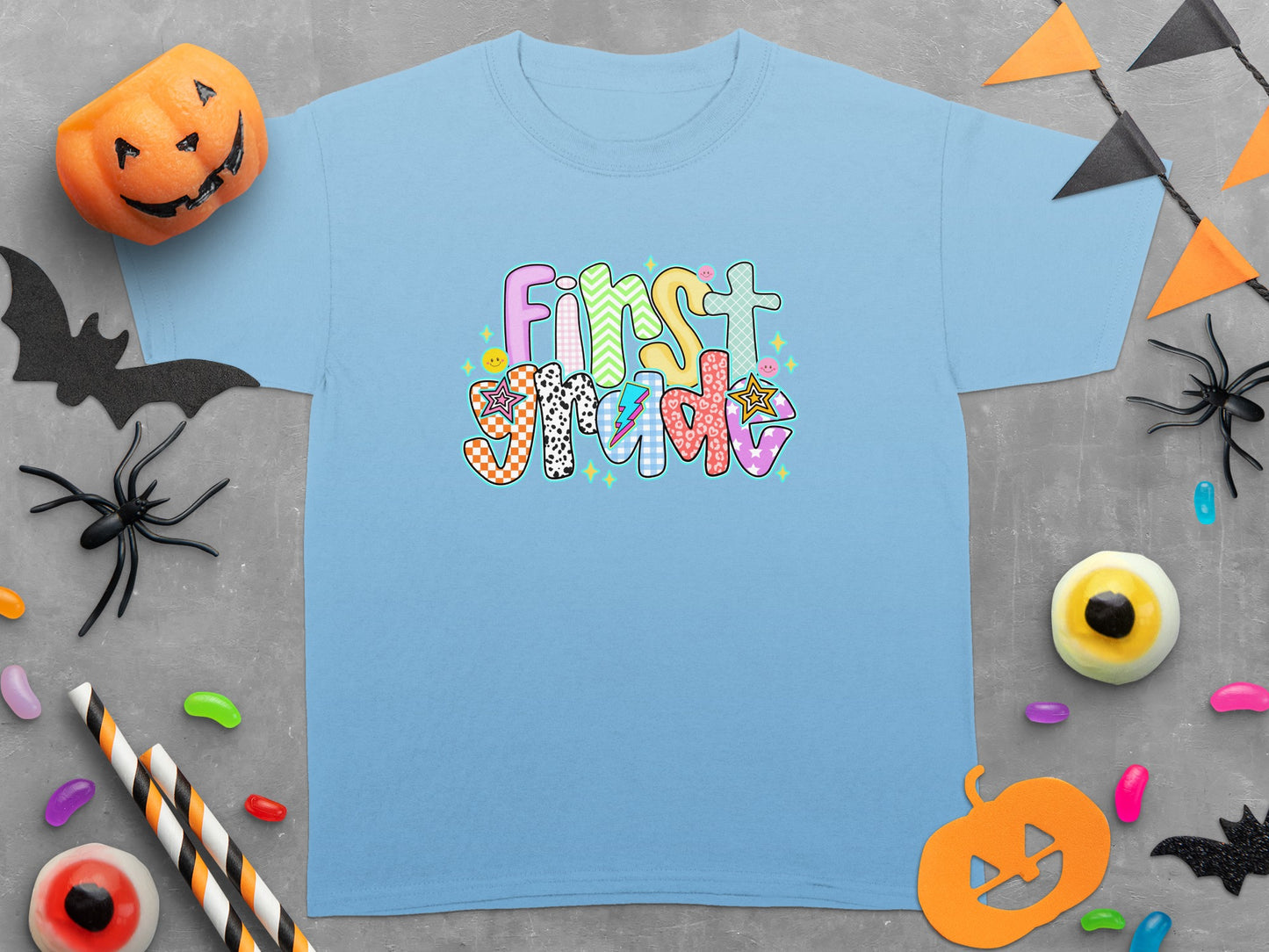 Light blue t-shirt with "First Grade" in colorful, patterned lettering.