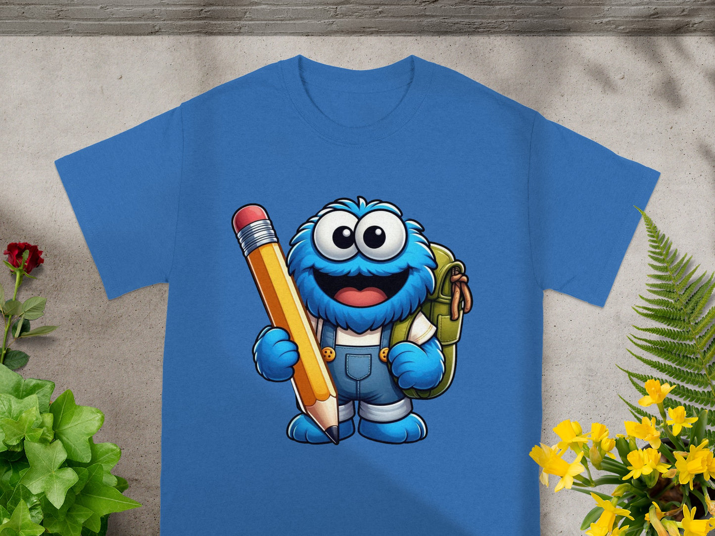 Blue t-shirt featuring cartoon Cookie Monster holding a large pencil and backpack.