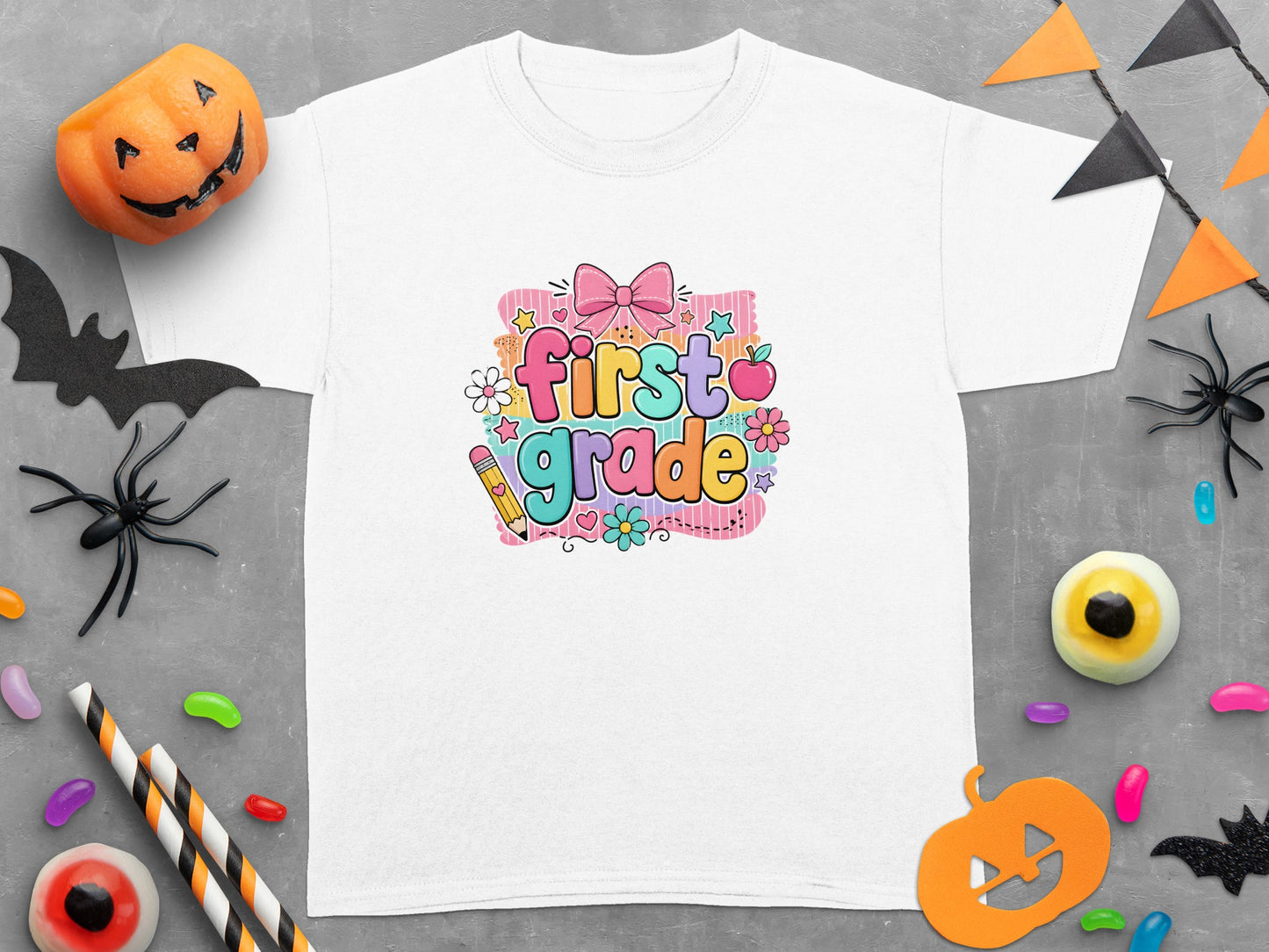 White t-shirt with colorful "first grade" text and Halloween-themed decorations.