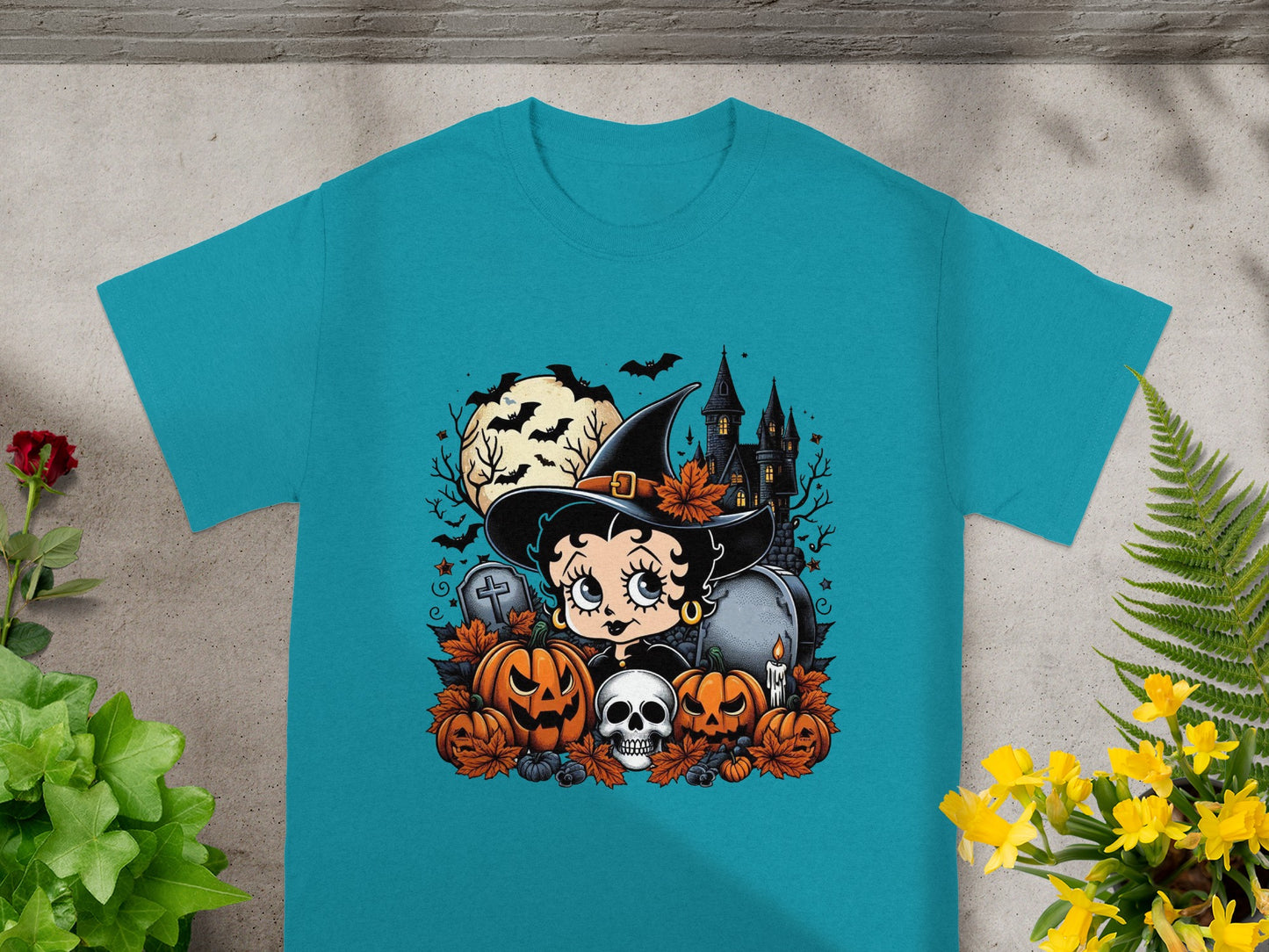 Betty Boop as a witch with pumpkins, skull, and haunted castle Halloween graphic.