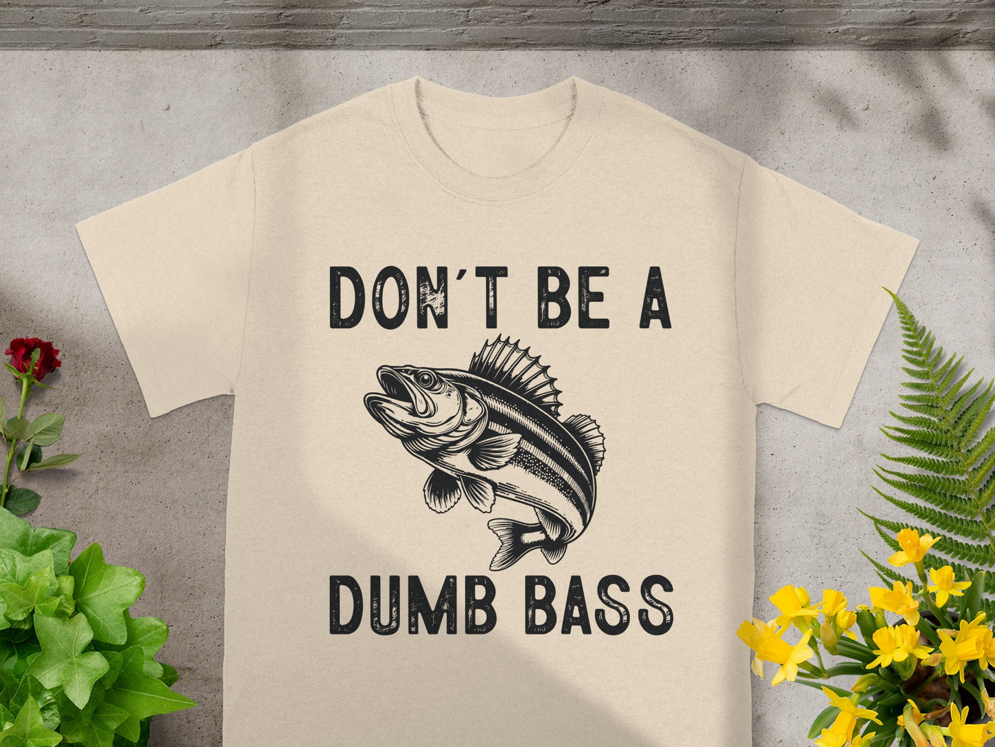 Light beige t-shirt with black text "DON'T BE A" and a fish illustration above "DUMB BASS".