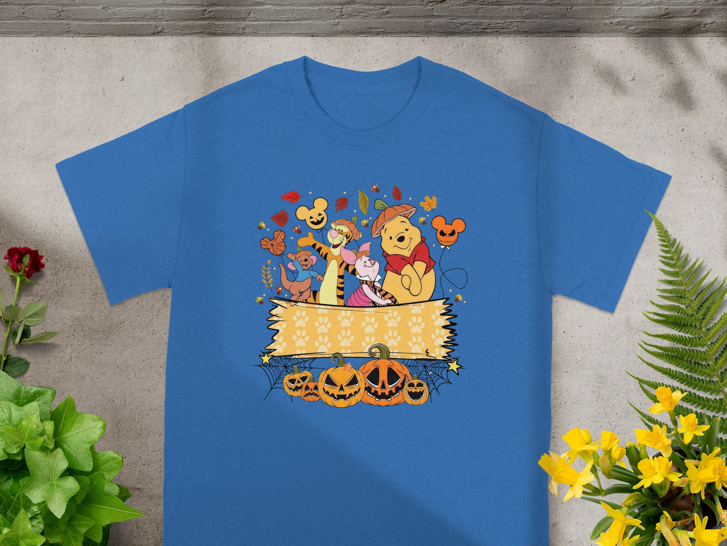 Winnie the Pooh characters with Halloween pumpkins and autumn leaves on a blue shirt.