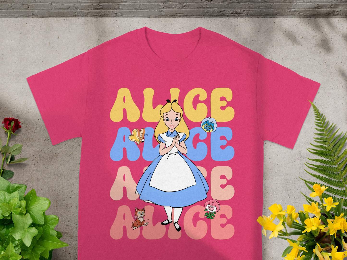 Pink t-shirt with Alice in Wonderland characters and text.