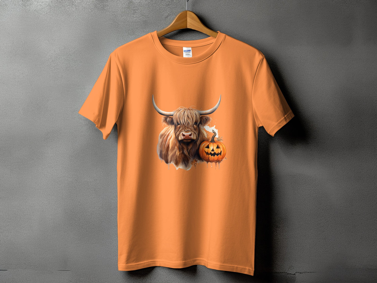 Orange t-shirt with a Highland cow and a jack-o'-lantern graphic.