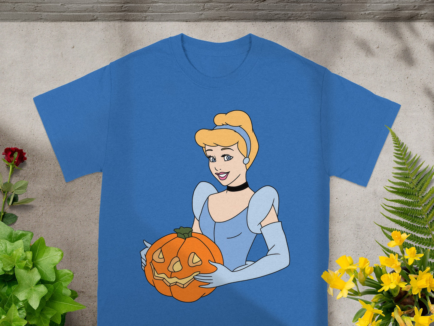 Cinderella holding a carved Halloween pumpkin on a blue t-shirt.