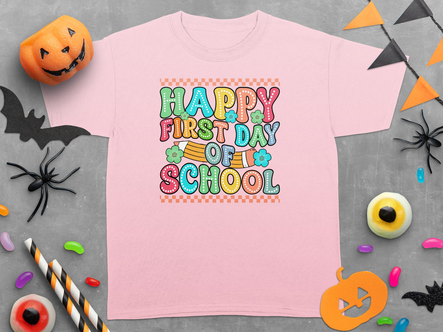 Pink t-shirt with "Happy First Day of School" text in colorful bubble letters.