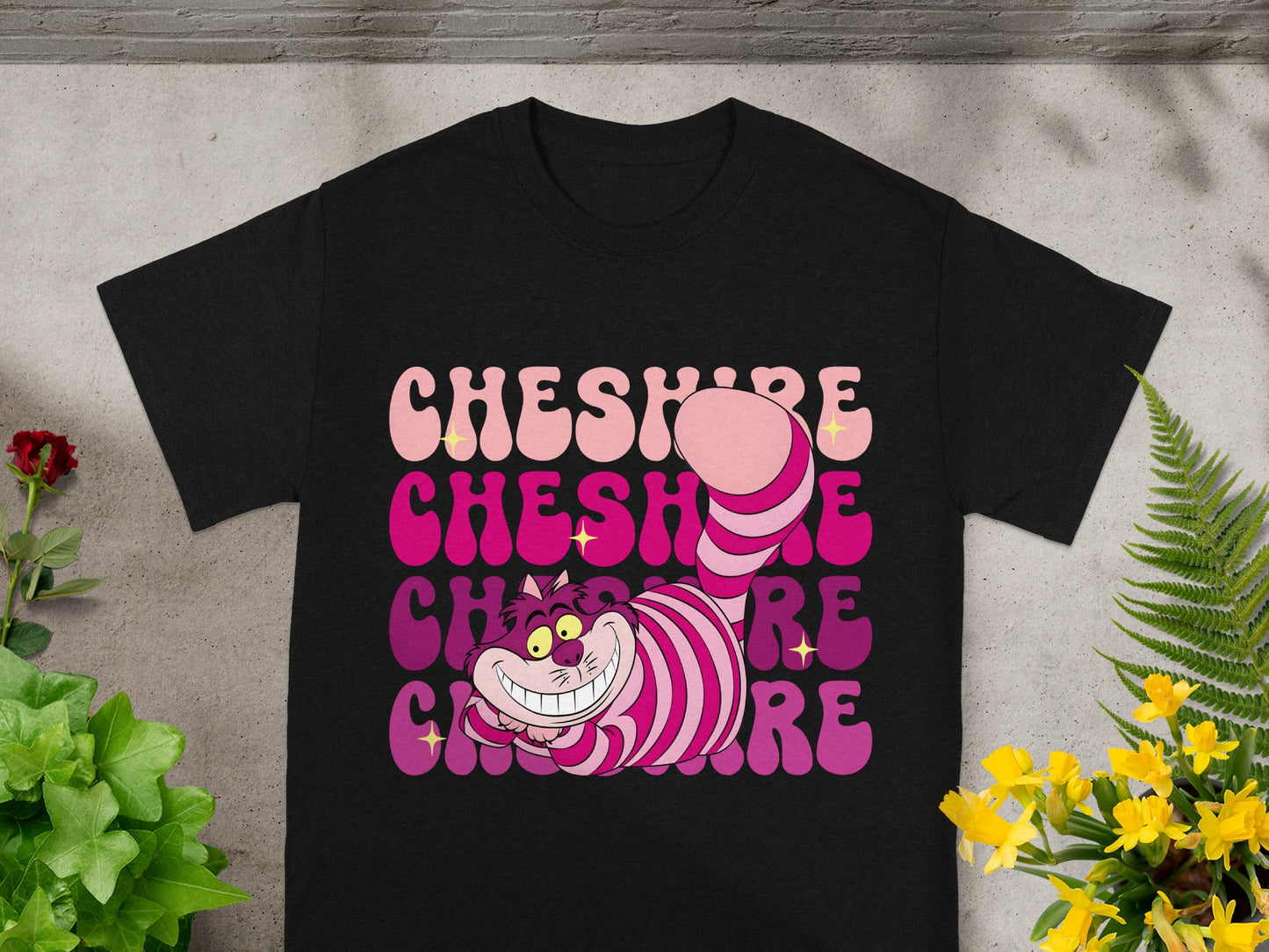 Black t-shirt with gradient "Cheshire" text and cartoon Cheshire Cat graphic.