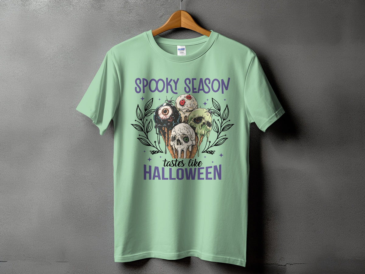 Light green t-shirt with "Spooky Season tastes like Halloween" and skull ice cream cones.