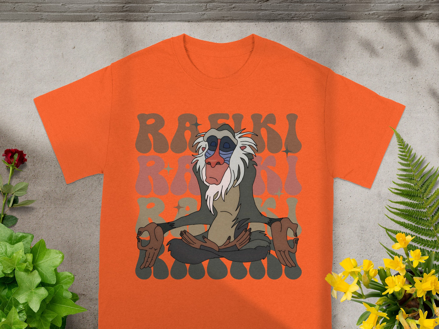 Rafiki meditating on orange t-shirt with colorful Rafiki text background.