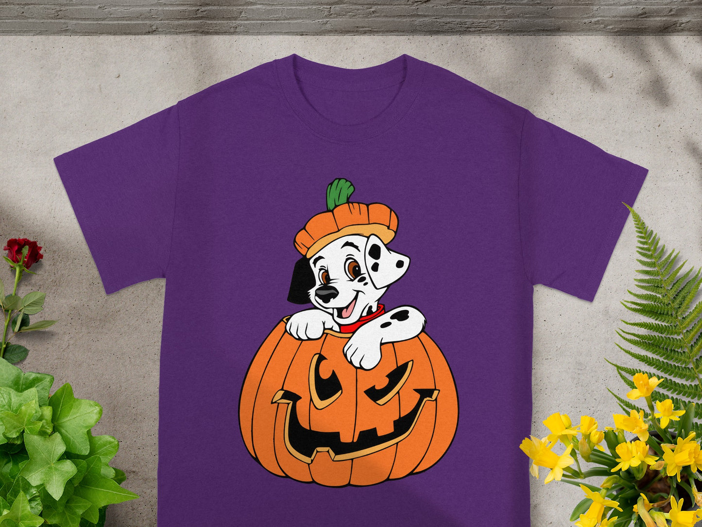 Dalmatian puppy in a pumpkin wearing a hat, on a purple t-shirt.