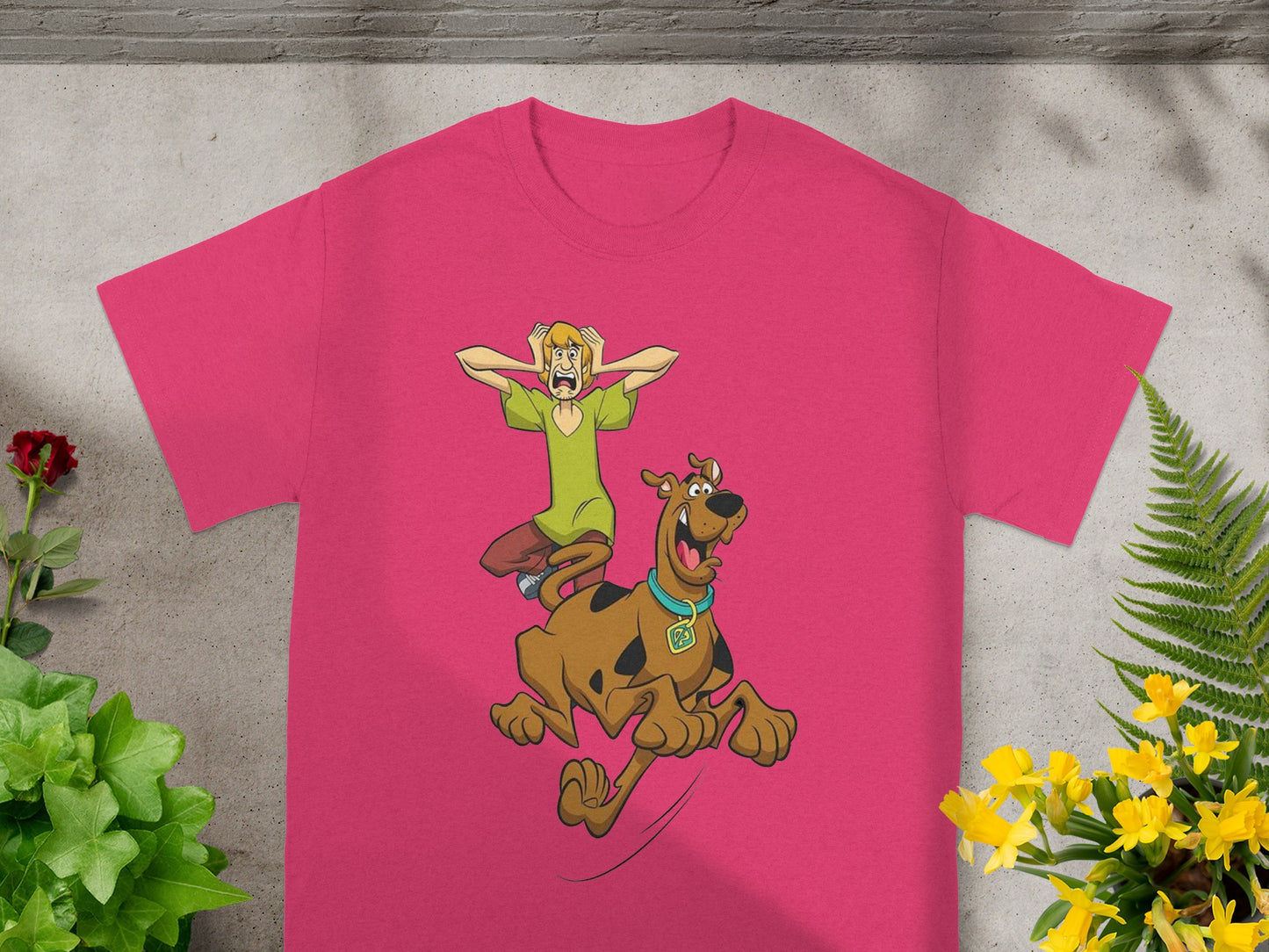 Scooby-Doo and Shaggy running with green grass background on a pink t-shirt.
