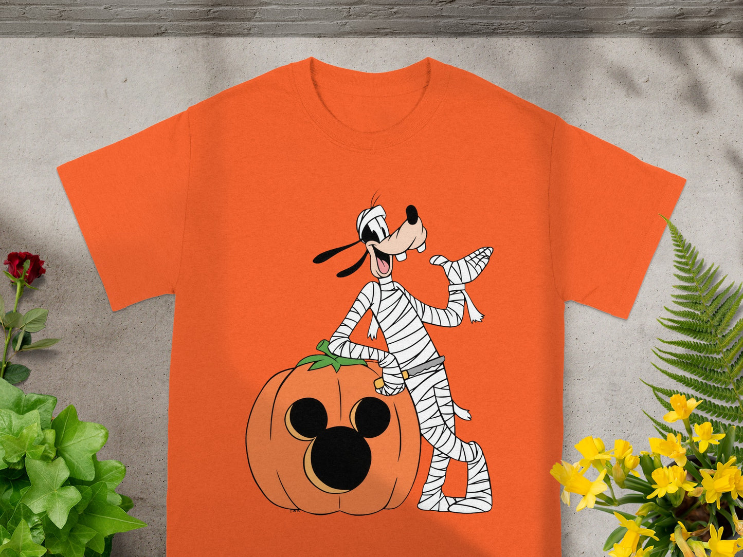 Orange t-shirt with Goofy dressed as a mummy leaning on a pumpkin.