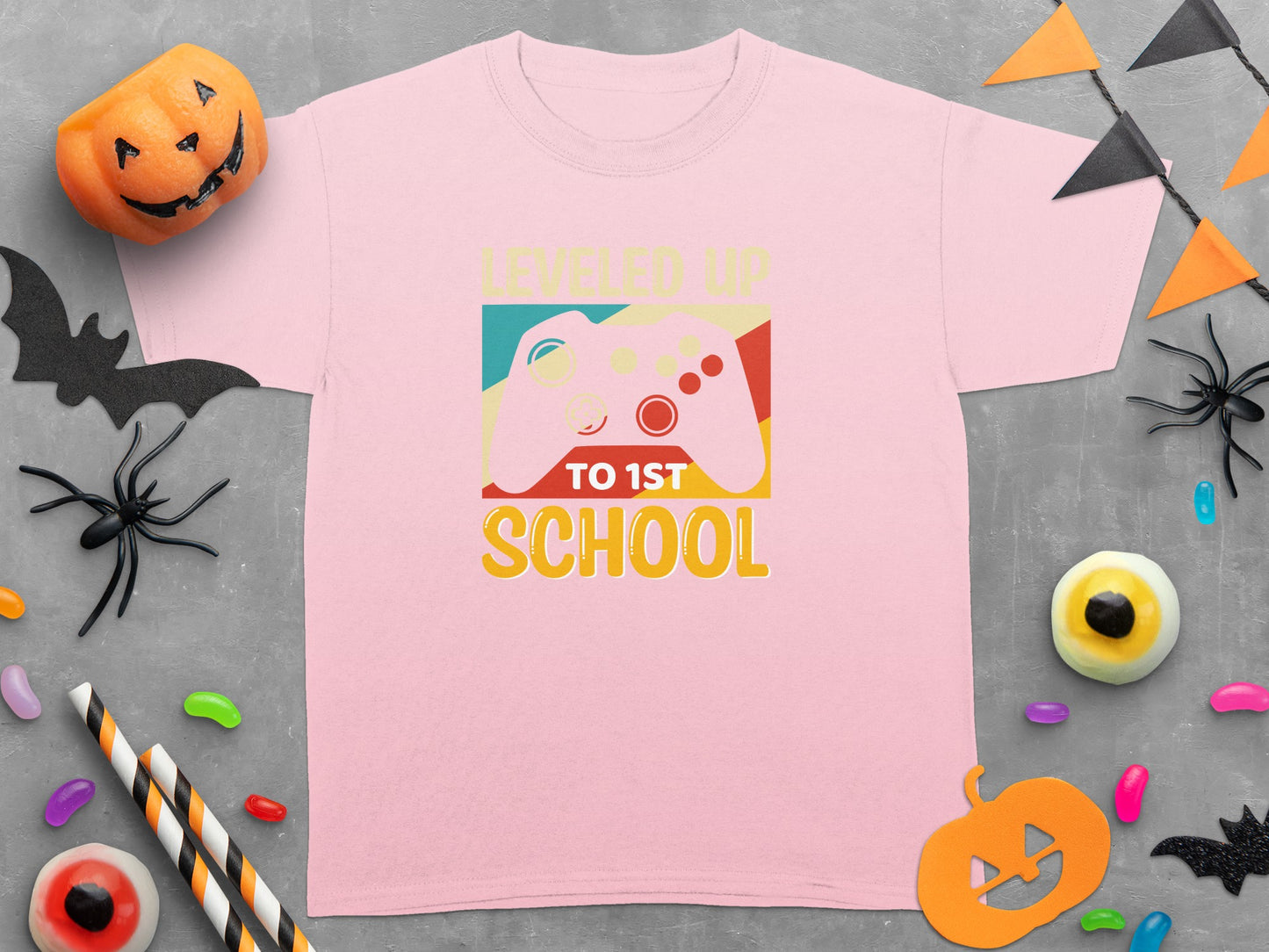 Pink t-shirt with a graphic of a controller and text "LEVELED UP TO 1ST SCHOOL."