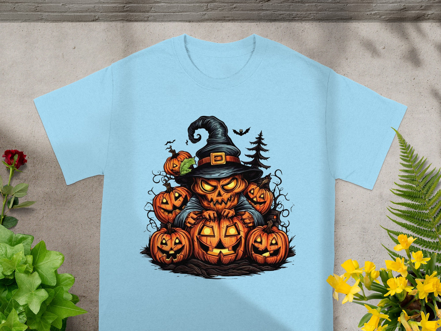 Scary jack-o'-lantern witch surrounded by pumpkins and bats, printed on a light blue t-shirt.