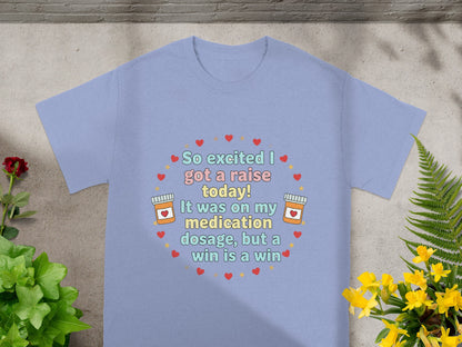 Light blue t-shirt with heart and pill graphics and "So excited I got a raise today!" text.