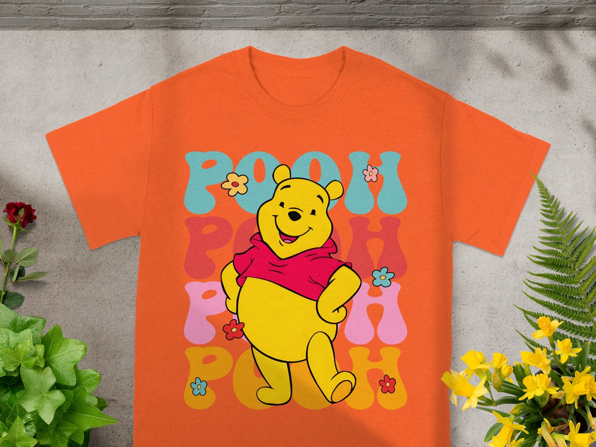 Winnie the Pooh wearing a red sweater, smiling with colorful text.