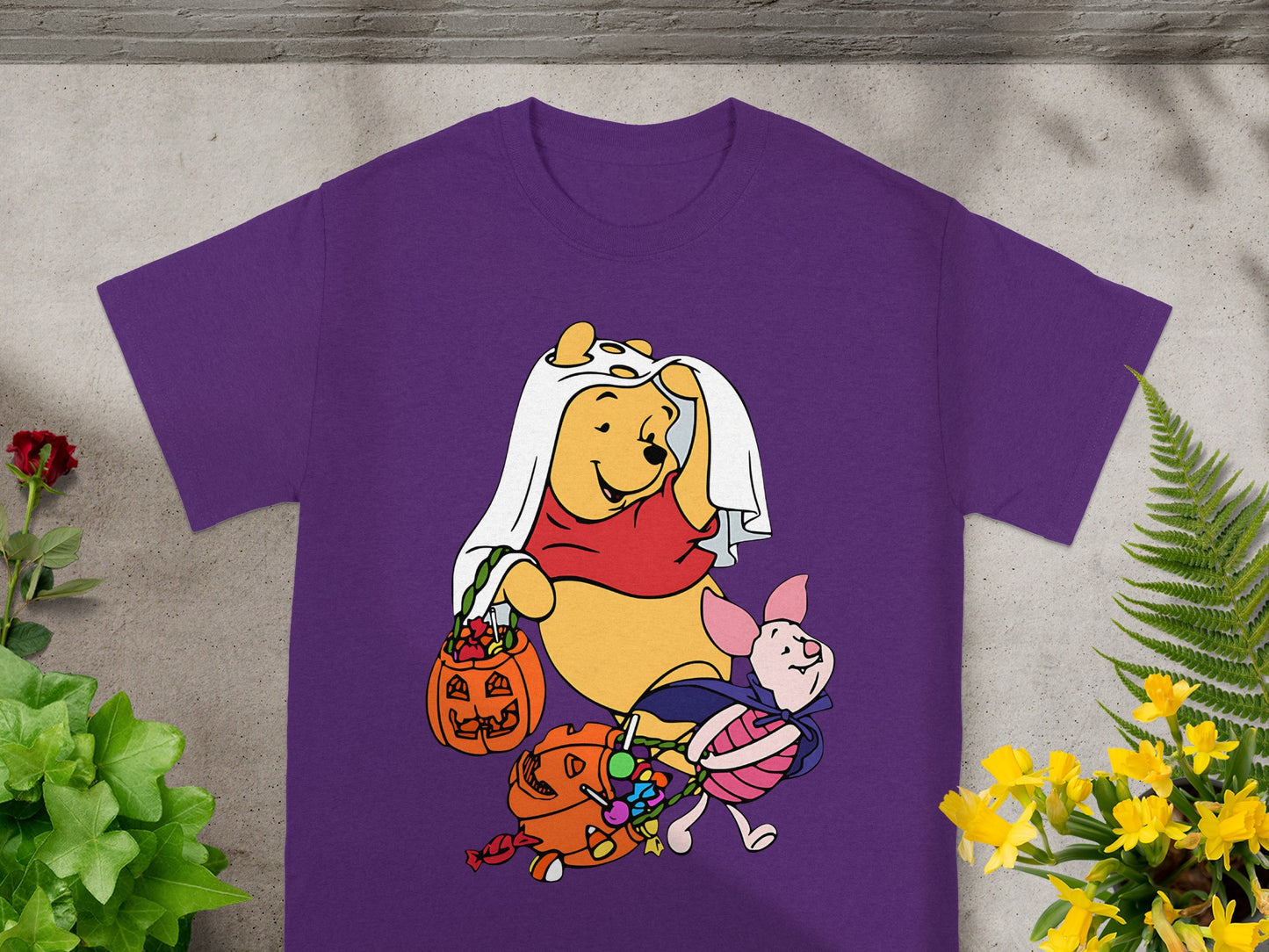 Winnie the Pooh and Piglet trick-or-treating in Halloween costumes on a purple shirt.