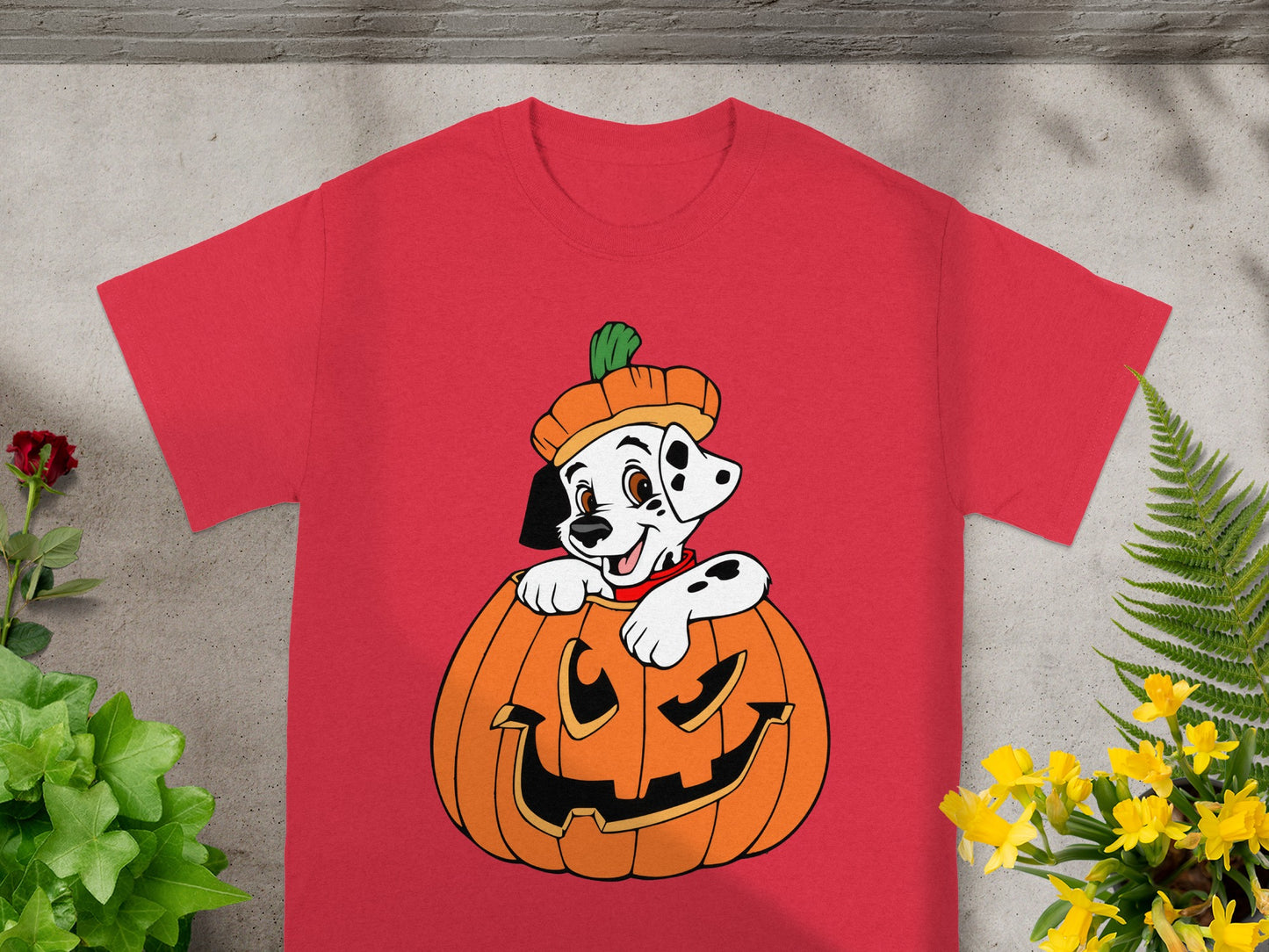 Dalmatian puppy in a pumpkin hat peeking out of a jack-o'-lantern on a red shirt.