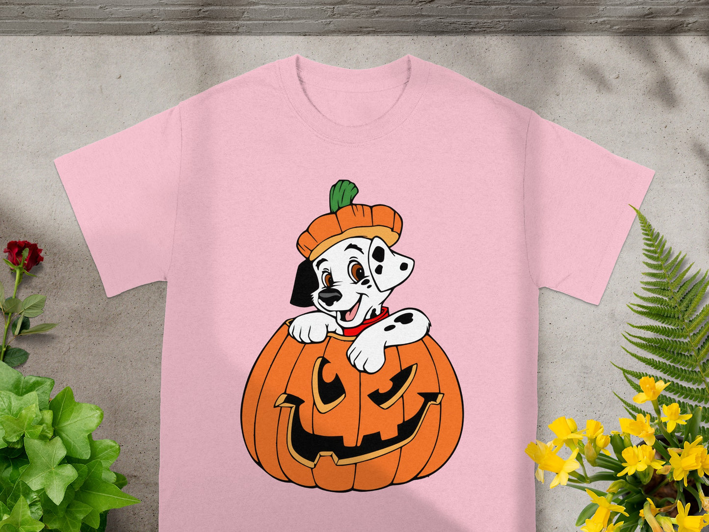 Dalmatian puppy peeking out of a jack-o'-lantern on a pink t-shirt.