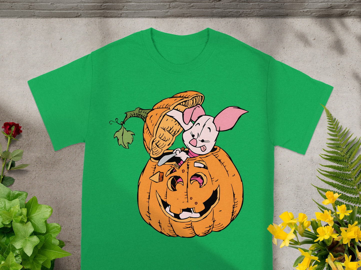 Piglet in a jack-o'-lantern on a green t-shirt.