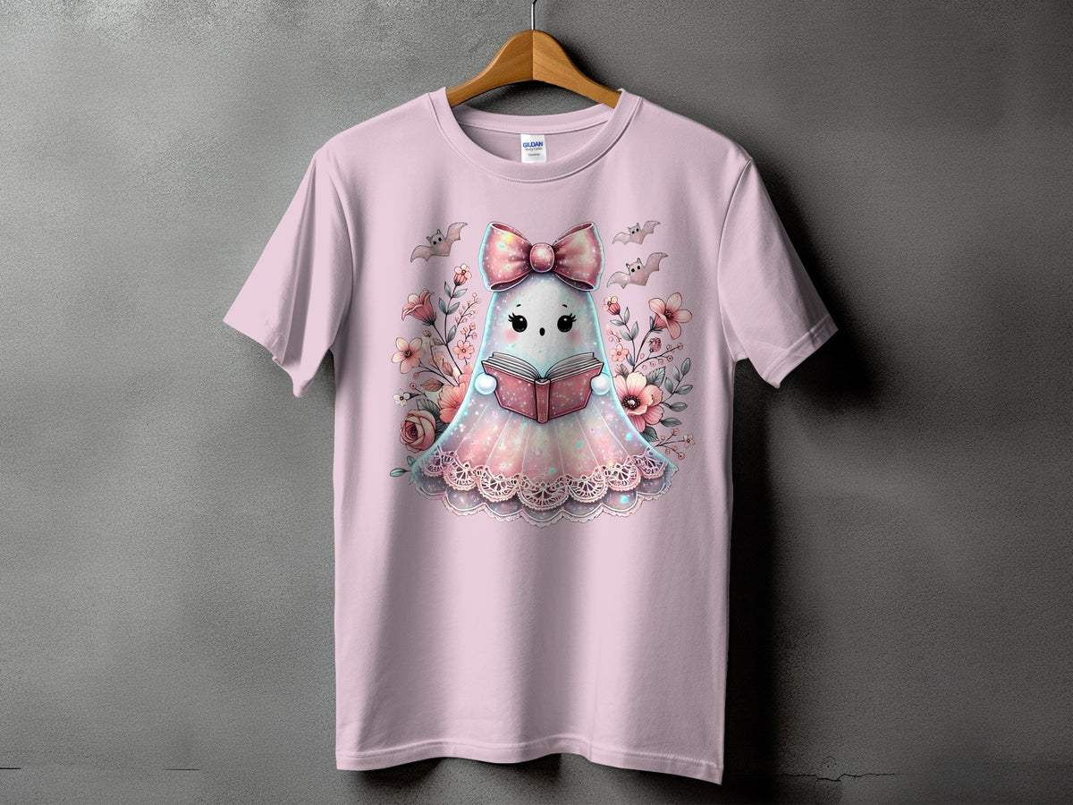Pink t-shirt with a cute ghost character reading a book surrounded by flowers and bats.
