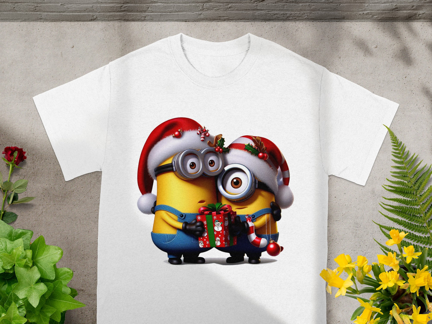 Two Minions in Santa hats hold a gift and candy cane on a white t-shirt.