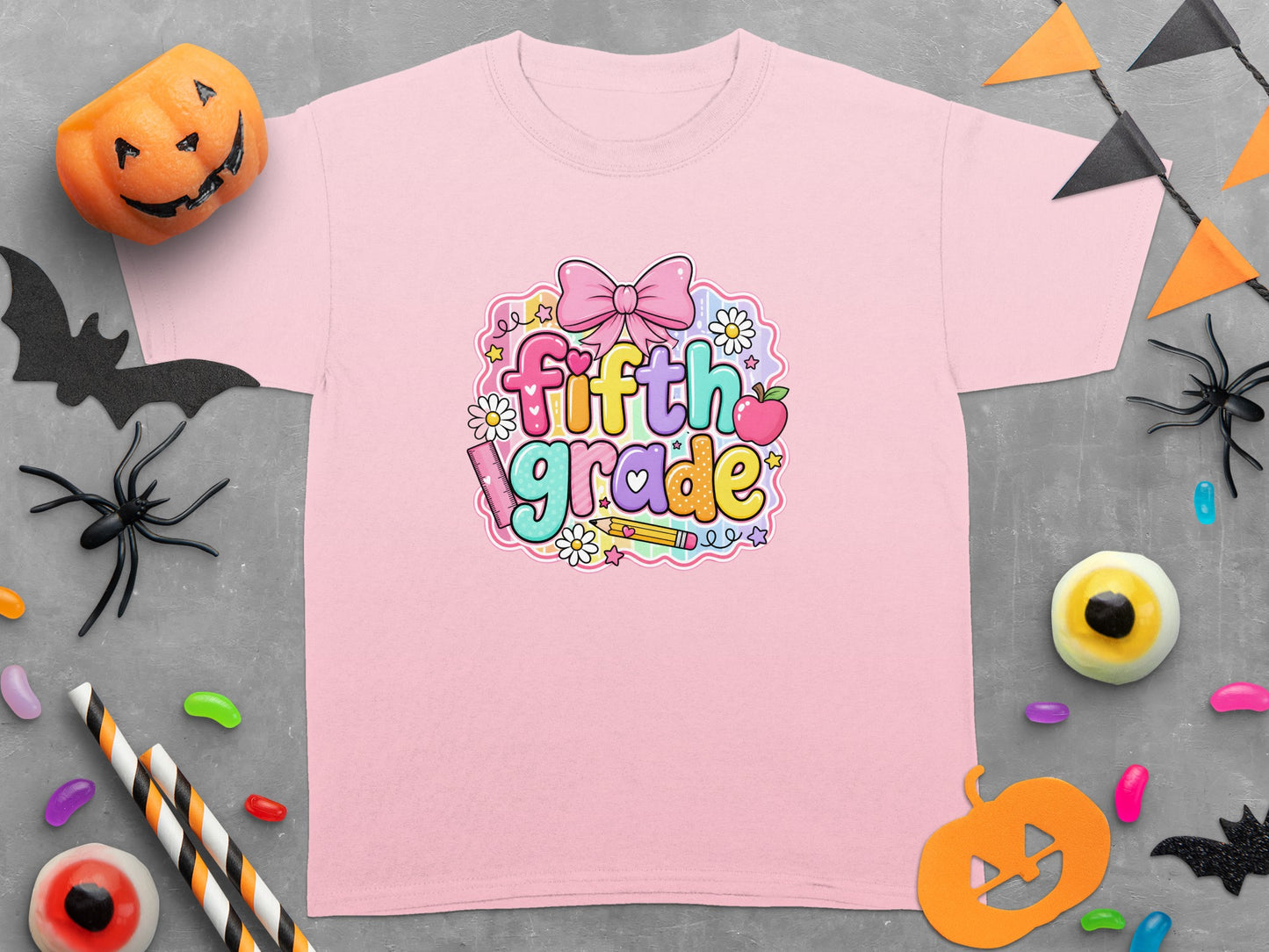 Pink t-shirt with "fifth grade" graphic surrounded by school and Halloween decorations.