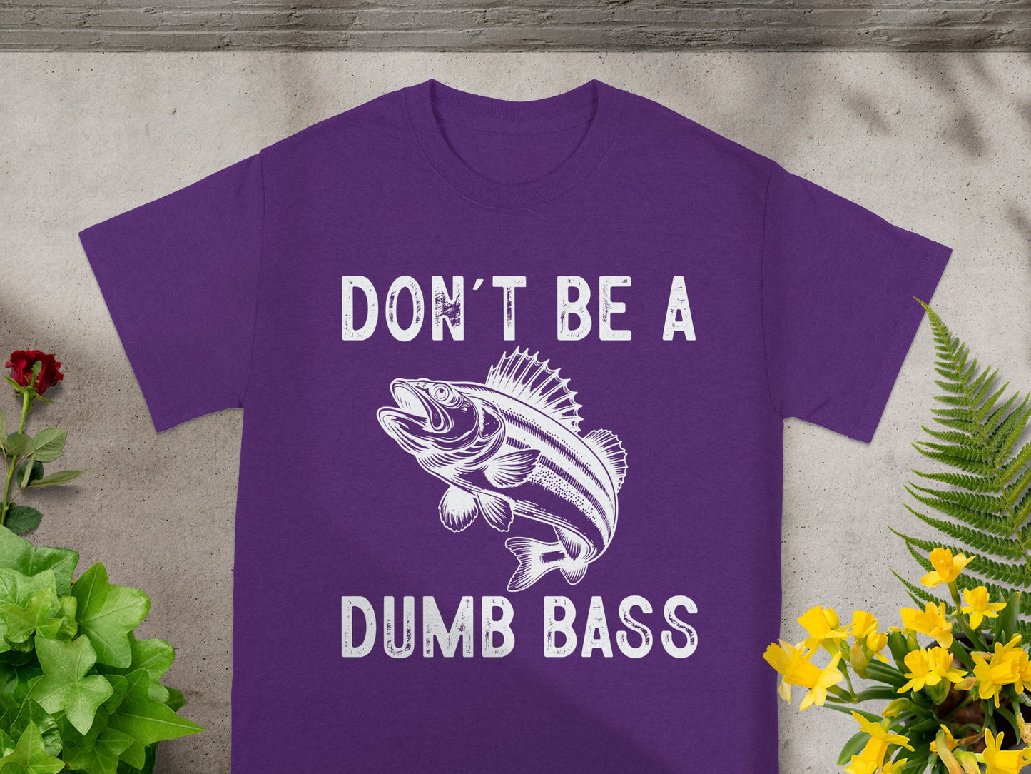 Purple t-shirt with white text "DON'T BE A DUMB BASS" and a bass fish graphic.