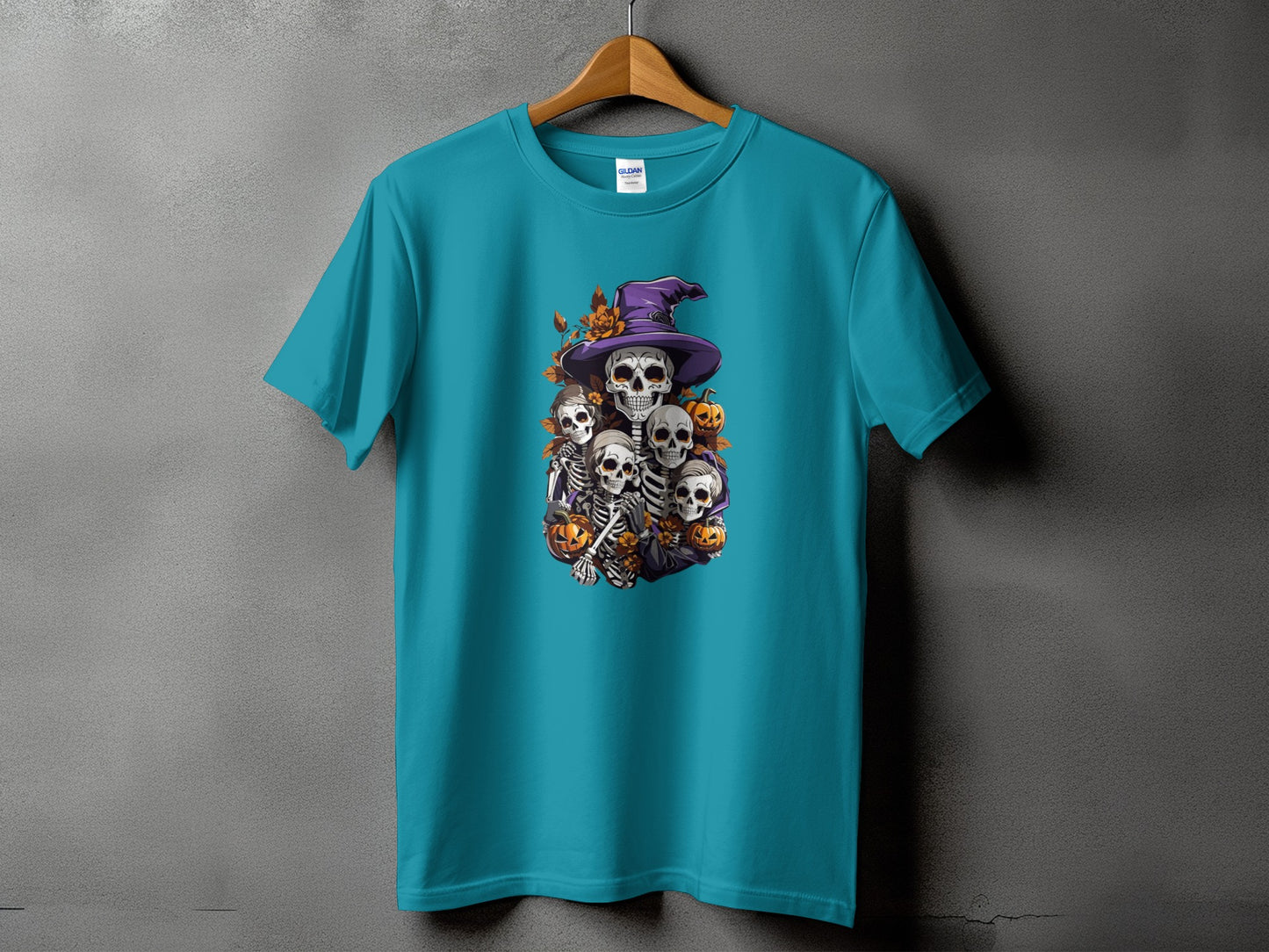 Teal t-shirt with a Halloween graphic of multiple skeletons and pumpkins.